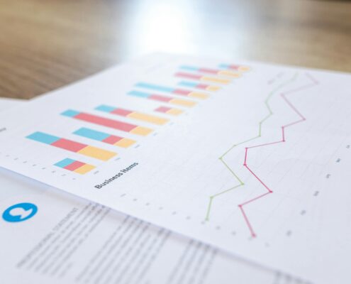 Close-up of printed business reports showing colorful bar charts and line graphs with life coaching statistics and trends.