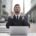 A determined man in a business suit sitting at a laptop outdoors, clenching his fists in a moment of emotional resilience or triumph, symbolizing overcoming setbacks through inner strength.