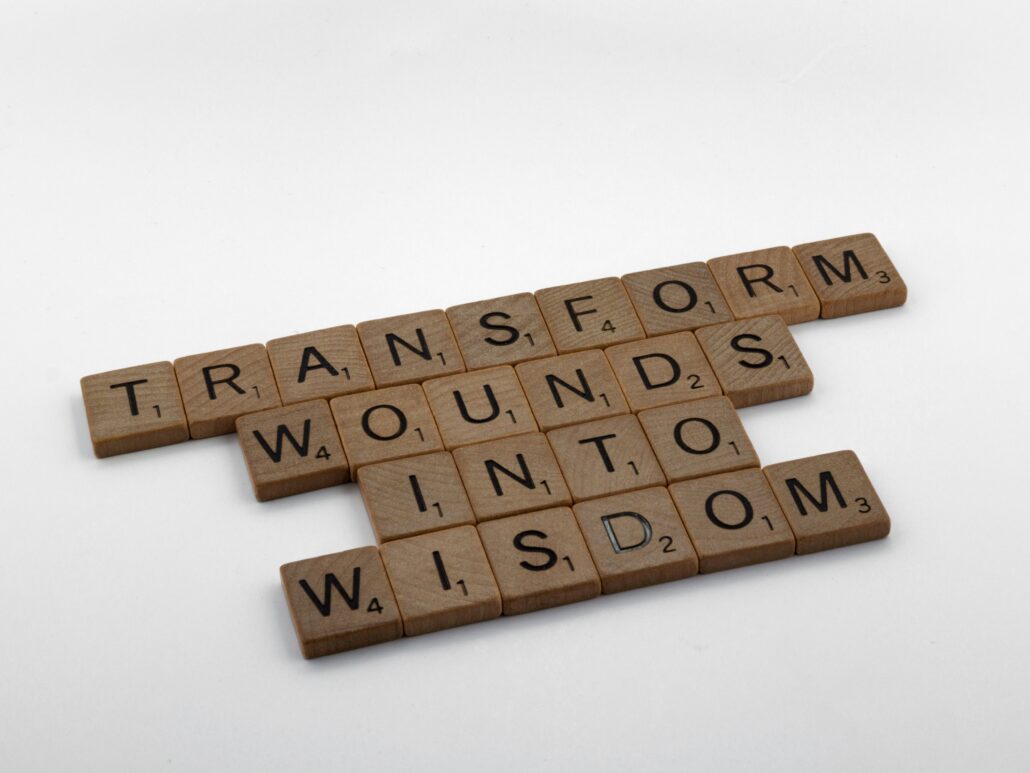 Scrabble tiles spelling 'Transform wounds into wisdom,' representing the science behind coaching and personal transformation.