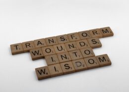 Scrabble tiles spelling 'Transform wounds into wisdom,' representing the science behind coaching and personal transformation.
