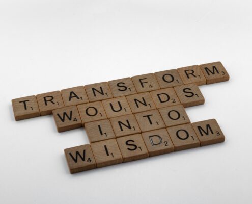 Scrabble tiles spelling 'Transform wounds into wisdom,' representing the science behind coaching and personal transformation.