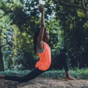 Somatic coaching practice with a woman performing a grounded yoga lunge outdoors, focusing on body awareness, movement, and mind-body connection