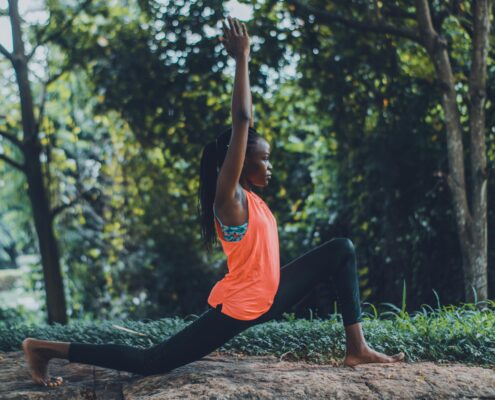 Somatic coaching practice with a woman performing a grounded yoga lunge outdoors, focusing on body awareness, movement, and mind-body connection