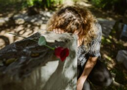 Woman grieving at a gravesite with a red rose, representing grief coaching techniques for coaches supporting clients through loss