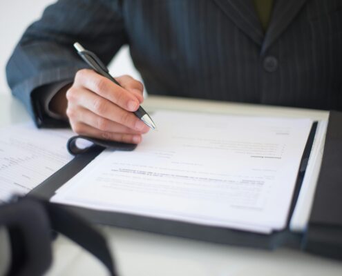Person signing official documents about life coach licensing requirements and certification