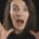 A surprised woman with wide eyes and open mouth holds her hands near her face against a dark background, expressing shock and anxiety—illustrating coaching fear of failure and the emotional overwhelm that can come with self-doubt.