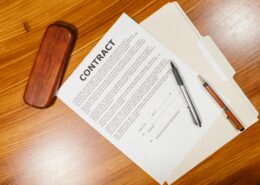 Coaching contract document on a desk with pens and a folder, representing a formal coaching agreement that outlines responsibilities, expectations, confidentiality, and terms of engagement.