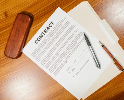 Coaching contract document on a desk with pens and a folder, representing a formal coaching agreement that outlines responsibilities, expectations, confidentiality, and terms of engagement.