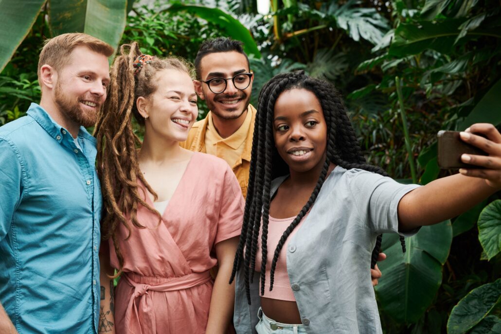 A diverse group of young professionals takes a cheerful selfie outdoors, reflecting connection and confidence through coaching millennials.