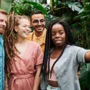 A diverse group of young professionals takes a cheerful selfie outdoors, reflecting connection and confidence through coaching millennials.