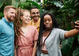 A diverse group of young professionals takes a cheerful selfie outdoors, reflecting connection and confidence through coaching millennials.