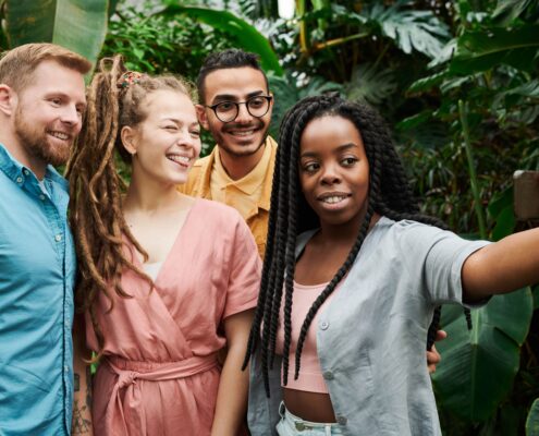 A diverse group of young professionals takes a cheerful selfie outdoors, reflecting connection and confidence through coaching millennials.