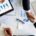 Two professionals shake hands over financial charts and business reports, illustrating how to start a life coaching business through planning, strategy, and partnership.