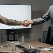 Corporate coaching professionals shaking hands during a business meeting in a modern conference room.
