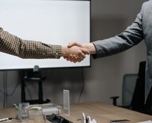 Corporate coaching professionals shaking hands during a business meeting in a modern conference room.