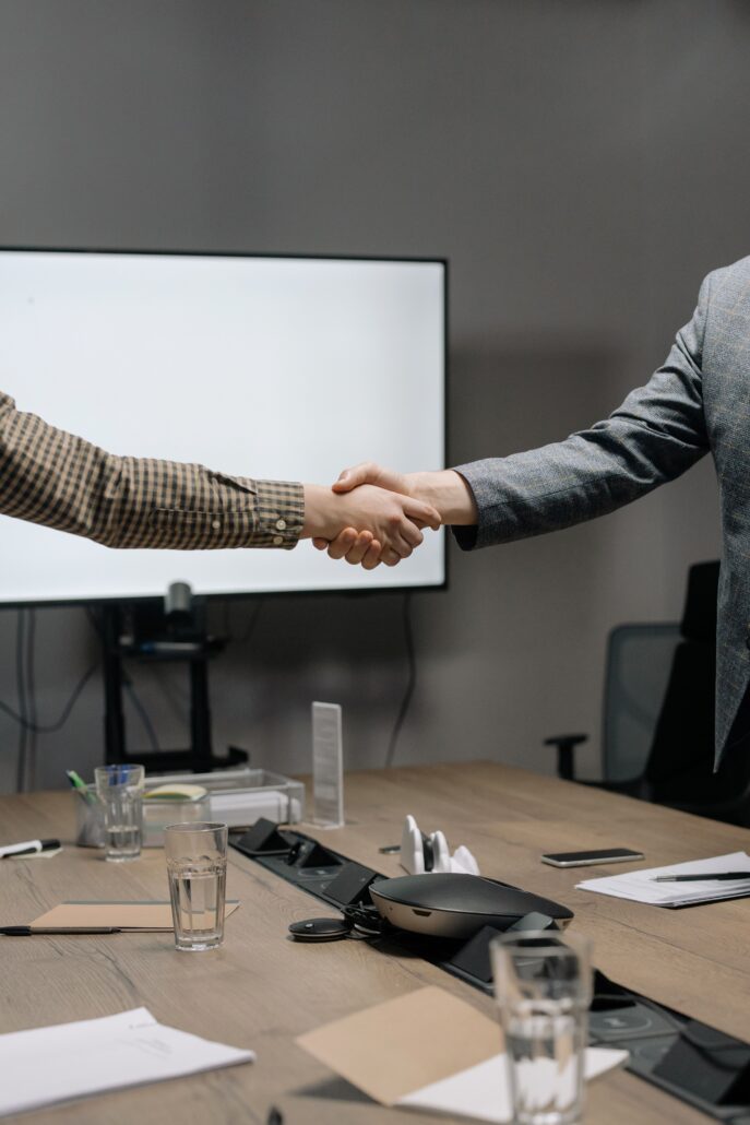 Corporate coaching professionals shaking hands during a business meeting in a modern conference room.