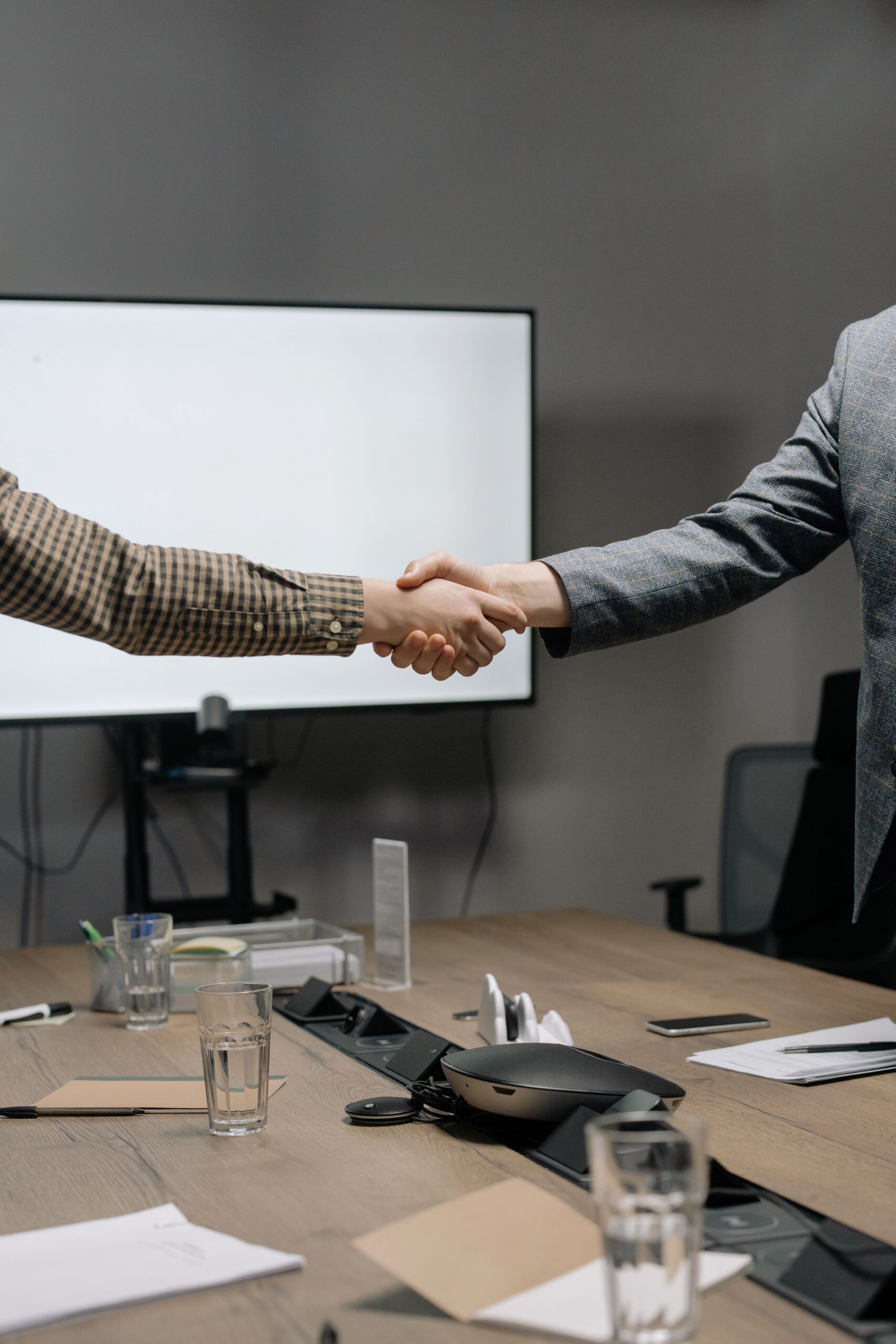 Corporate coaching professionals shaking hands during a business meeting in a modern conference room.