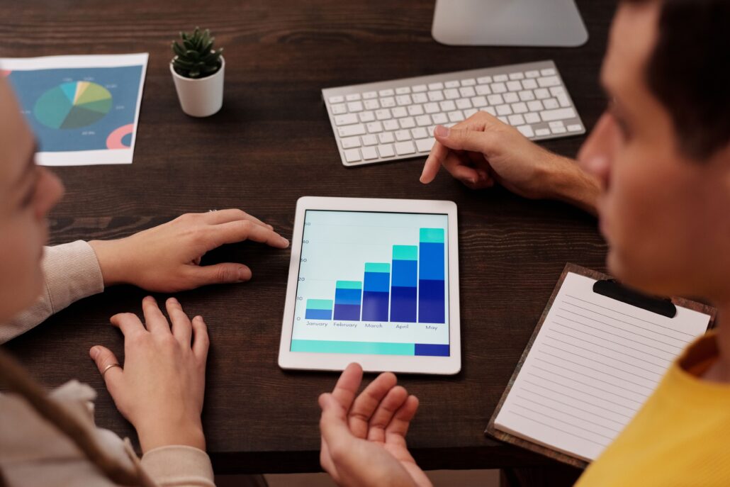 Two professionals reviewing growth charts on a tablet while discussing SEO for coaches and online marketing performance.