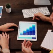 Two professionals reviewing growth charts on a tablet while discussing SEO for coaches and online marketing performance.