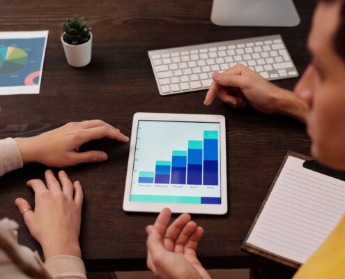 Two professionals reviewing growth charts on a tablet while discussing SEO for coaches and online marketing performance.